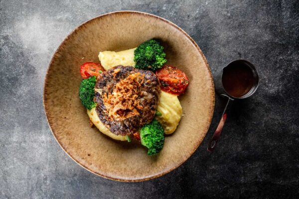 Lamb cutlet with rich mashed potatoes, broccoli, confit tomatoes, roasted onion, and red wine sauce